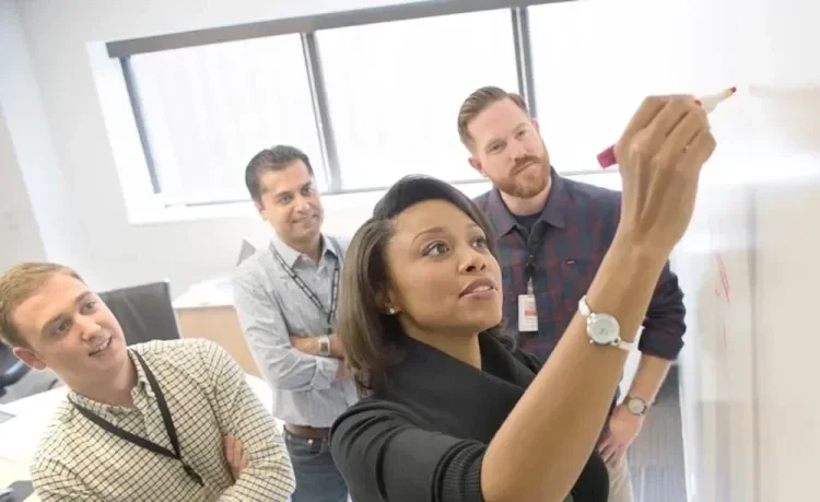 Gore associate writing on whiteboard in front of three colleagues