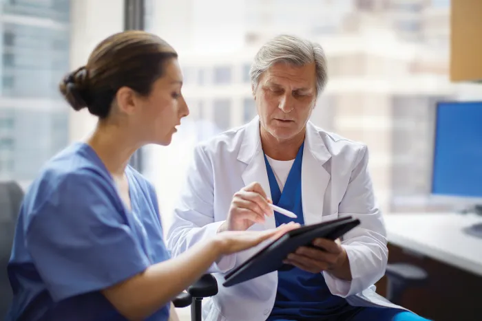 Doctor showing nurse information on tablet 